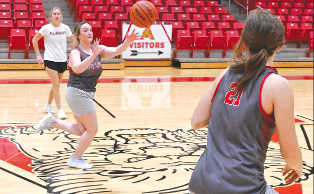 With head girls basketball coach Ashlyn Bevel (l) watching closely in the background, varsity Lady Lion Alli McDaniel (c) throws across the court to teammate Tatum Grady (r) during a Monday afternoon practice.