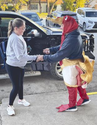 This year’s Turkey Teacher winner, Chris Beard (r), lets Kimberly Howe choose some candy as he greets students on Friday morning. The local ag teacher brought in $208 of the $308 raised during the fourth annual competition. Donn ie Lucas / Albany News