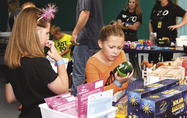 A couple of Fall Fest participants carefully look over and make their selections from the array of different level toys, games and other bounty on the tables at the prize booth. Despite rainfall in the days before the event, temperatures and weather on Saturday was good, and a large number of children and adults attended the PTO fundraiser. Donn ie Lucas / Albany News