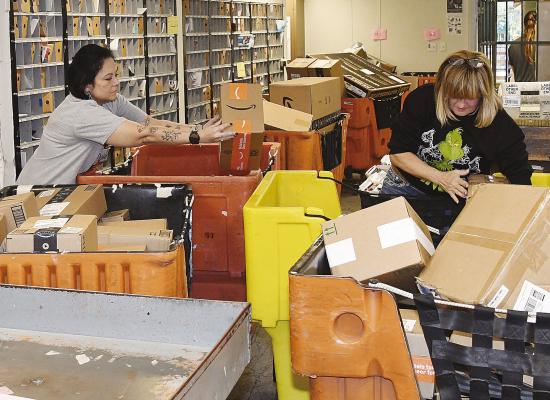 Stephanie Jaco (l) and Amy Price (l) start the process of sorting hundreds of boxes that come into the Albany post office each day during the busy holiday season. In addition to posting the mail and sorting packages, the postal workers keep up with letters to Santa. Donn ie Lucas / Albany News