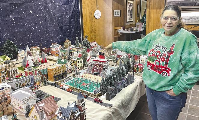 Cindy Parsons carefully arranges her Christmas village layout, a detailed miniature representation of Albany. She points out the details of the Robert Nail Memorial Stadium replica, complete with stadium lights and cheering fans
