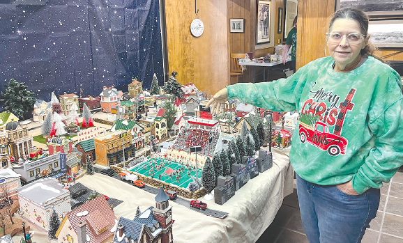 Cindy Parsons carefully arranges her Christmas village layout, a detailed miniature representation of Albany. She points out the details of the Robert Nail Memorial Stadium replica, complete with stadium lights and cheering fans